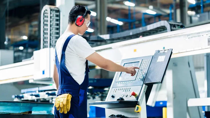 Worker operating a CNC lathe